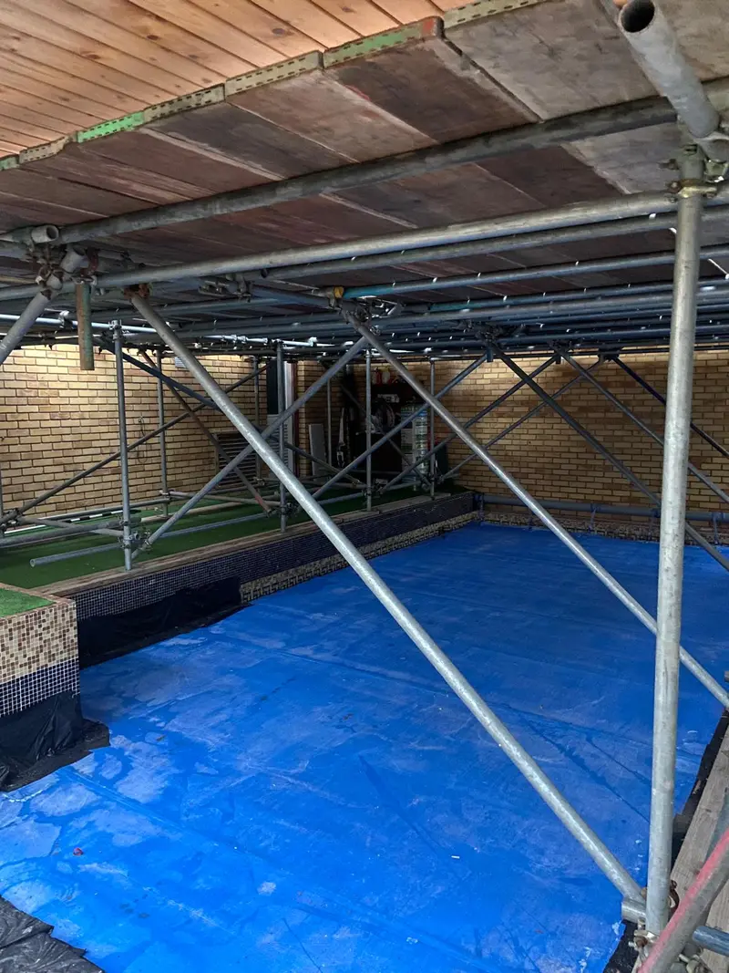 Bespoke crash-deck scaffold over a garden bar and putting green, protecting the surface below