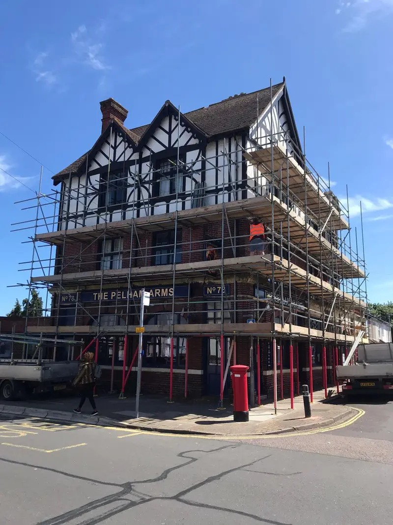 The Pelham Arms — Tudor-fronted pub wrapped in independent scaffold for a façade refurb