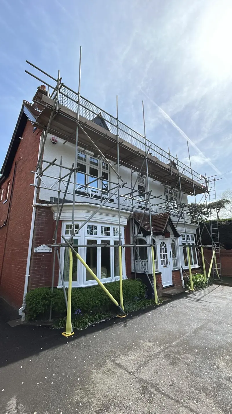 Arts-and-crafts front elevation wrapped in scaffold with bay-window transitions and full-height edge protection