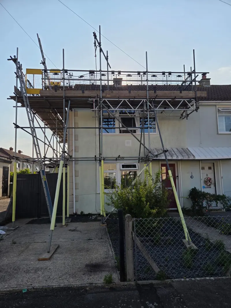 Front elevation of a semi-detached house in a full independent scaffold to roof level, with brick guards and a gin wheel on the top lift
