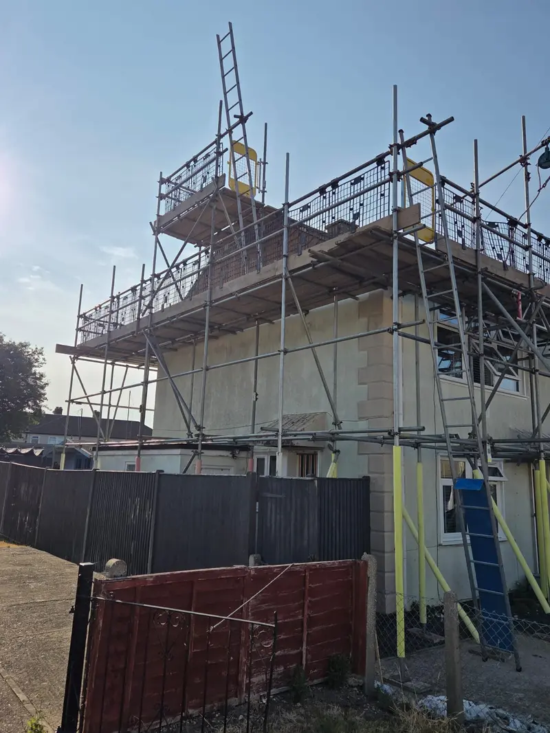 Gable end of the same house looking up the scaffold, ladder access to the top lift and double guardrails throughout